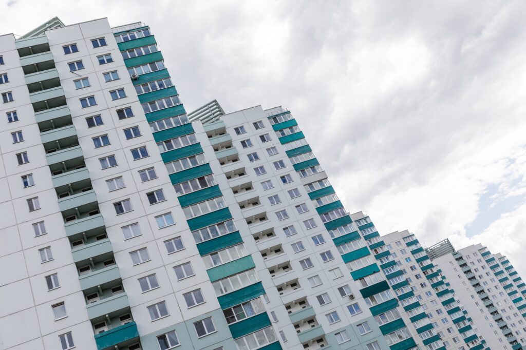 Gradually descending stepping building apartment of white colour and green balcony on gray sky