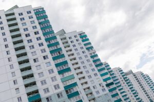 Gradually descending stepping building apartment of white colour and green balcony on gray sky